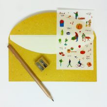 Setting with envelope in yellow organic paper, pencil, sharpener and stickers