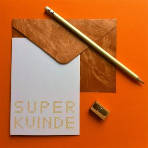 Setting with "Super Kvinde" postcard in yellow with envelope, pencil and pencil sharpener